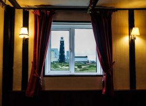 Blick aus doppelverglastem Kneipenfenster auf einen Leuchtturm