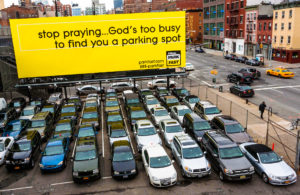 Werbung für einen Parkplatz ist überschrieben mit „stop praying… God‘s too busy to find you a parking spot“.
